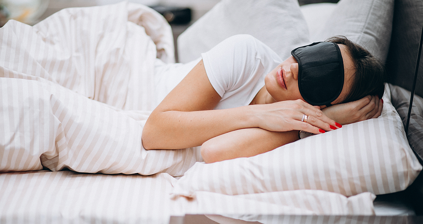 vrouw ligt in bed met een oogmasker op vrouw ligt in bed met een oogmasker op