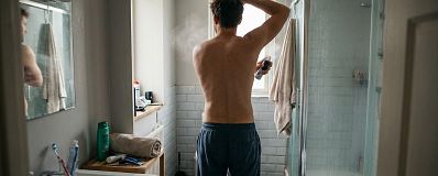 Man brengt deodorant spray aan in de badkamer