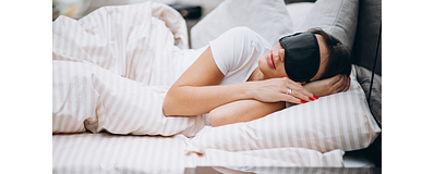 vrouw ligt in bed met een oogmasker op