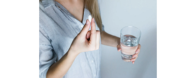 vrouw die diclofenac inneemt met glas water in haar hand vrouw die diclofenac inneemt met glas water in haar hand