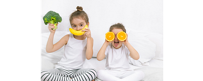 twee meisjes op bed met groente en fruit twee meisjes op bed met groente en fruit