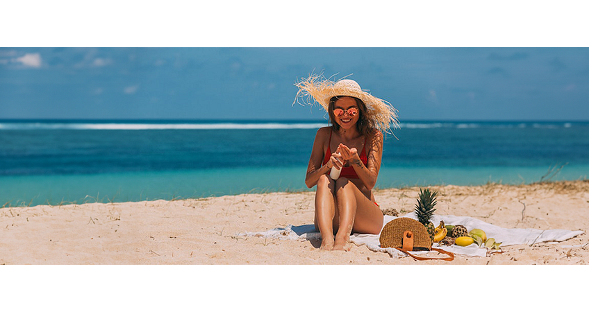vrouw op strand die zich insmeert met zonnebrand