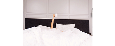 persoon in bed steekt een kopje koffie boven de deken uit