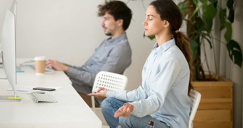 vrouw die er ontspannen uitziet achter haar bureau, omdat de ademhalingsoefeningen doet vrouw die er ontspannen uitziet achter haar bureau, omdat de ademhalingsoefeningen doet