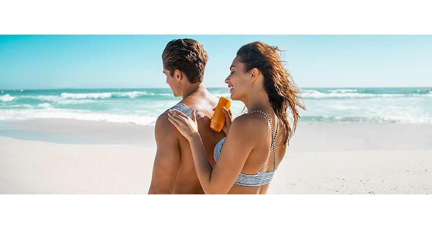 Vrouw smeert man in met zonnebrand aan strand Vrouw smeert man in met zonnebrand aan strand