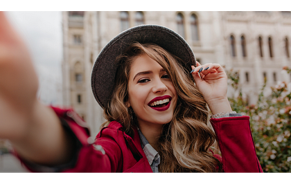 vrouw lachend, met een hoed op en rode lippenstift